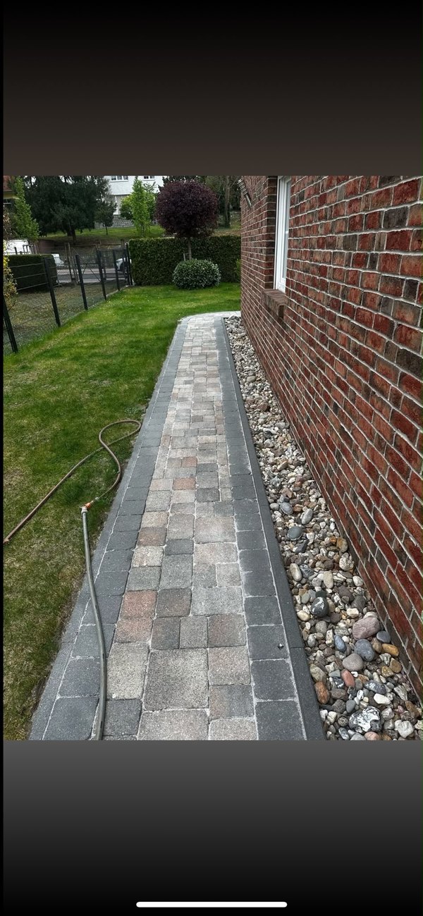 Gereinigter Gartenweg aus Pflastersteinen entlang einer Klinkerfassade — echtes Kundenfoto